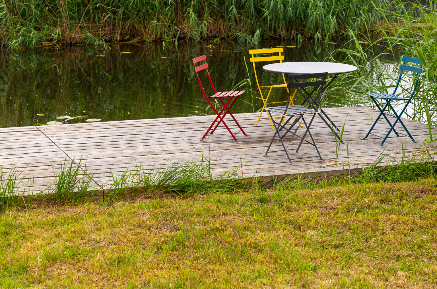 Ferienhaus, privater Steg an der Peene mit Gartentisch und Stühlen