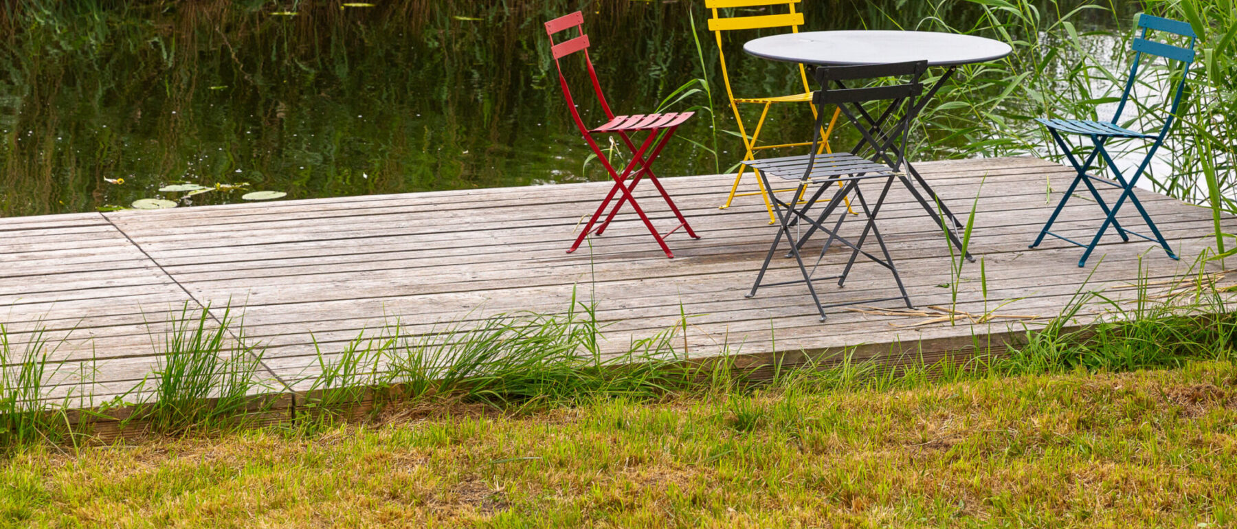 Ferienhaus, privater Steg an der Peene mit Gartentisch und Stühlen