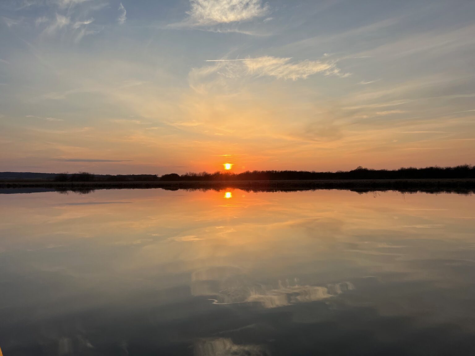 Sonnenaufgang mit Spiegelung auf ruhigem Wasser