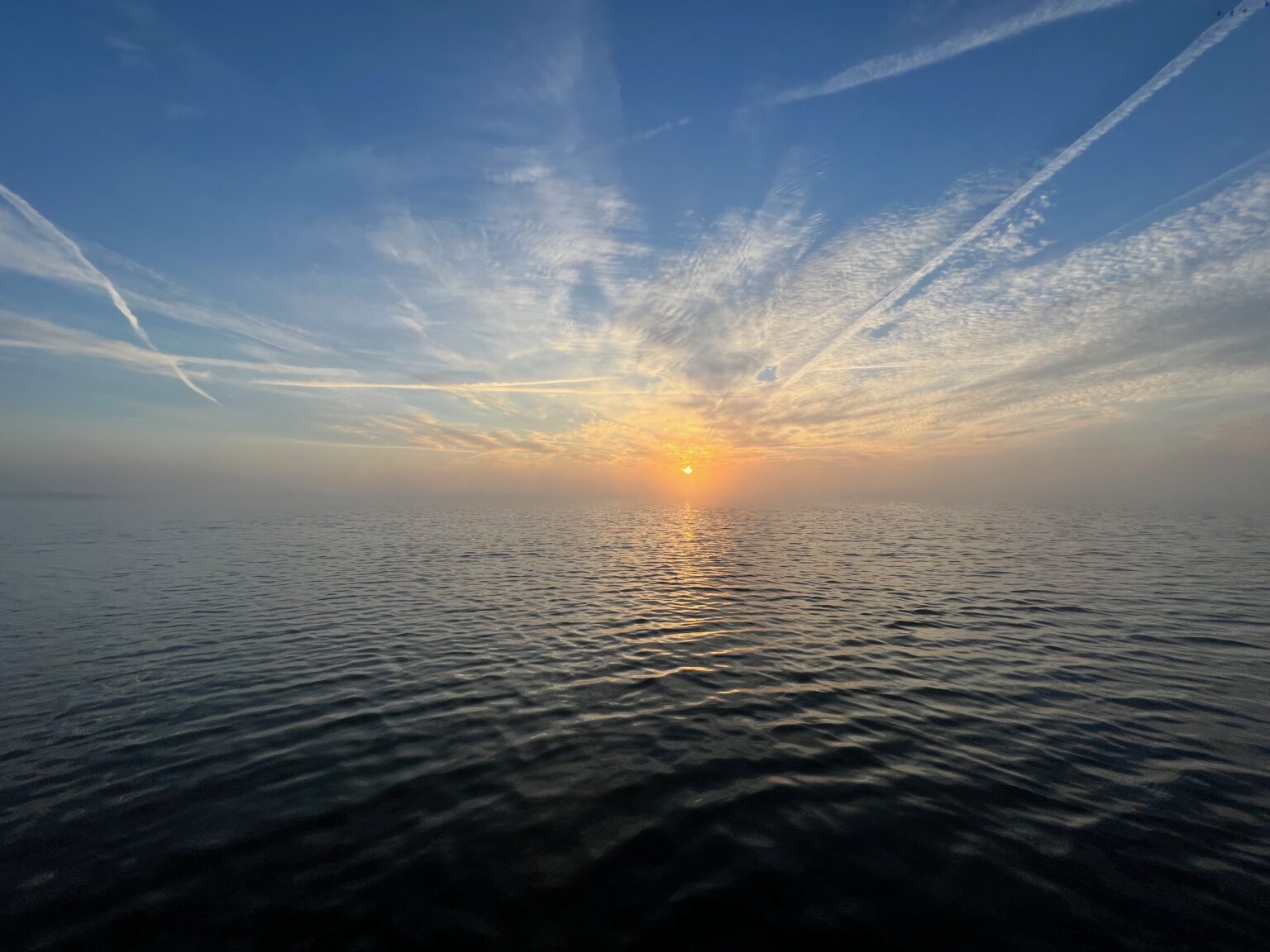 Sonnenaufgang spiegelt sich auf ruhigem Wasser des Kummerower Sees