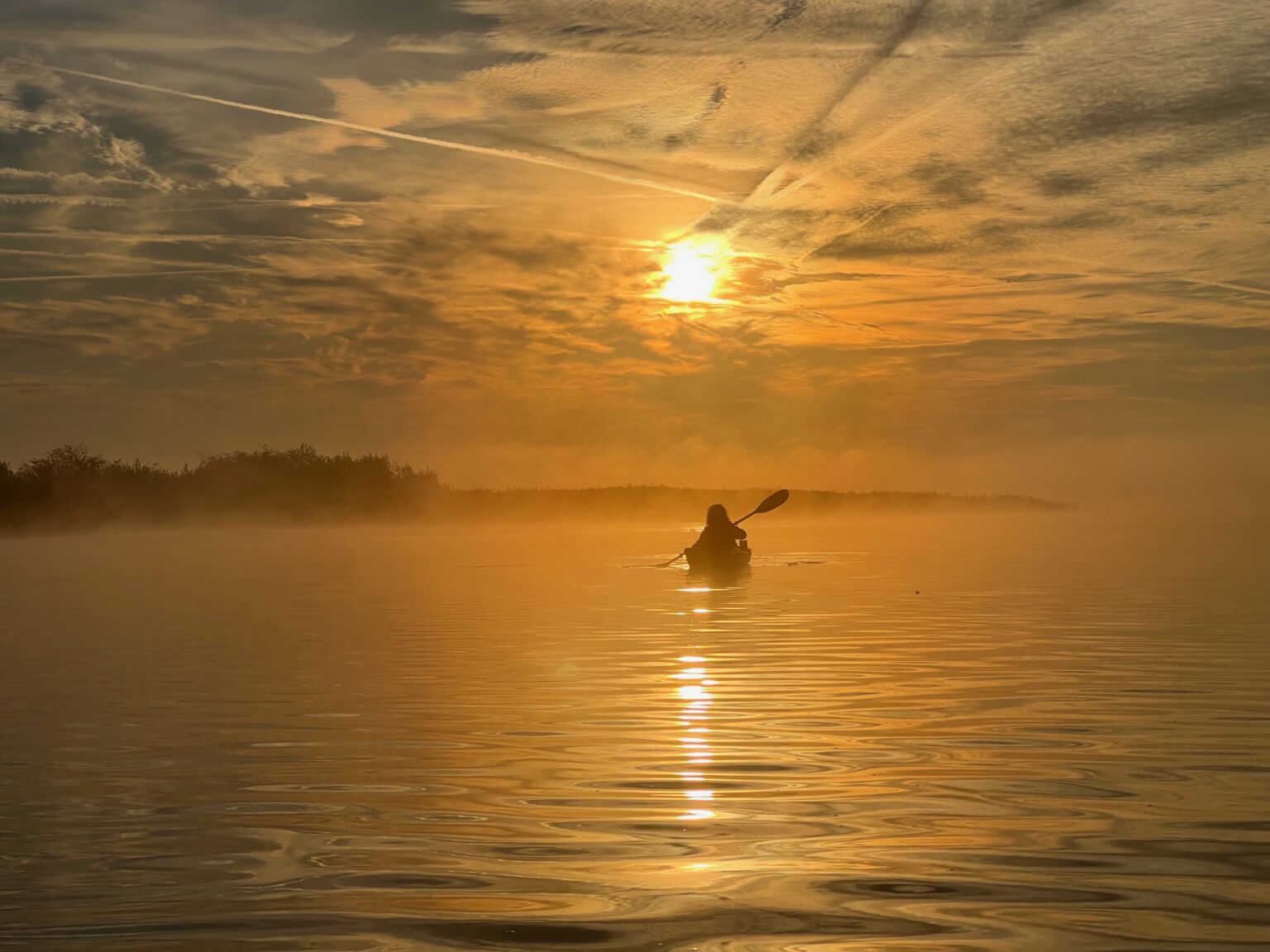 Paddelboot vor der aufsteigenen Sonne auf dem Kummerower See